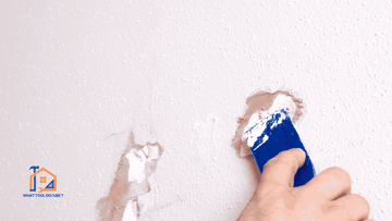 person filling a hole in a white wall with filler